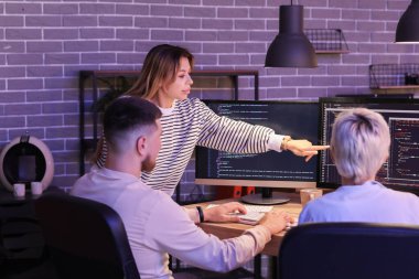 Meslektaşlarıyla birlikte geceleri ofiste çalışan kadın programcı.