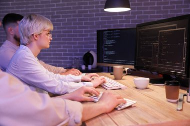 Meslektaşlarıyla birlikte geceleri ofiste çalışan kadın programcı.