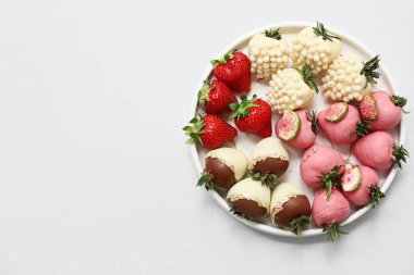 Çikolata kaplı çilekli tabak ve gri arka planda taze böğürtlen.