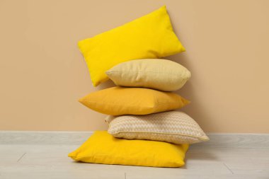 Bej duvarın yanındaki yastık yığını.