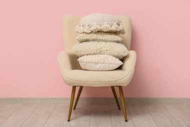 Odadaki pembe duvarın yanındaki koltukta bir yığın yastık.