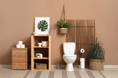 Seramik klozet, raf ünitesi ve tuvaletin içindeki bitkiler.