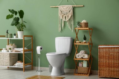 Tuvalet, raflar ve çamaşır sepeti tuvaletteki yeşil duvarın yanında.