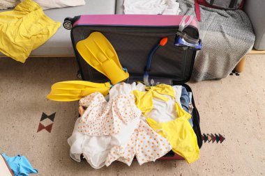 Oturma odasında üzerinde giysiler olan valizi aç.