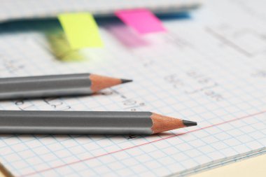 El yazısıyla yazılmış matematik formülleri ve sarı arkaplanlı kalemler, yakın plan