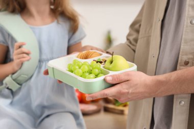 Babası küçük kızı için okul çantasıyla mutfağa yakın çekim yapıyor.