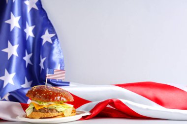 Beyaz arka planda ABD bayrakları olan lezzetli bir burger. Amerikan Bağımsızlık Günü kutlamaları