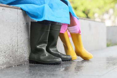 Yağmurlu havada yağmurluk ve çizme giyen çift.