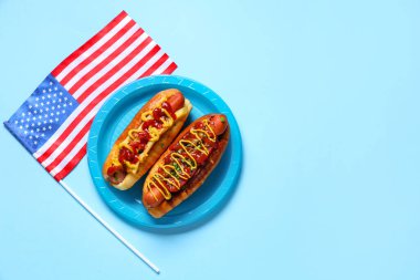 Lezzetli sosisli tabaklar ve mavi arka planda Amerikan bayrağı. Amerikan Bağımsızlık Günü kutlamaları