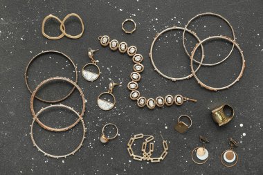 Siyah benekli arka planda farklı altın mücevherler. Üst görünüm