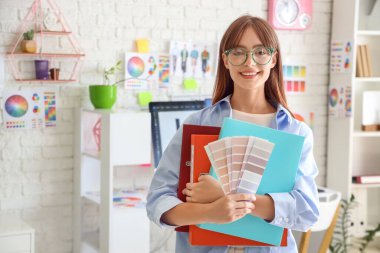 Ofisinde renk paletleri ve dizinleri olan kadın grafik tasarımcısı