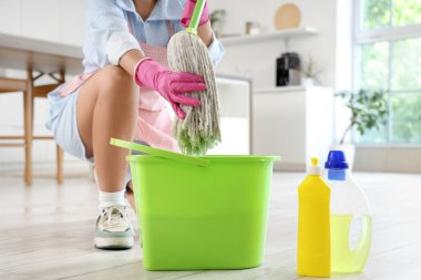 Mutfakta paspası ve kovası olan kadın, yakın plan.