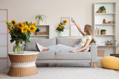 Evdeki klimayı açan vazolarla güzel, genç, mutlu bir kadın.