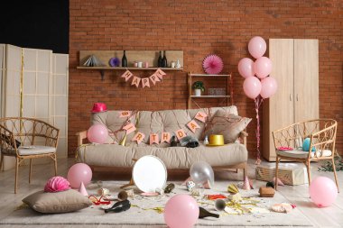 Doğum gününden sonra kanepe, koltuk ve parti dekoruyla dağınık oturma odasının içinde.