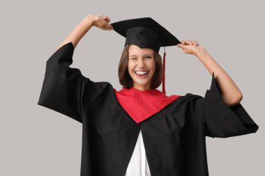 Gri arka planda mezun olan mutlu bayan öğrenci.