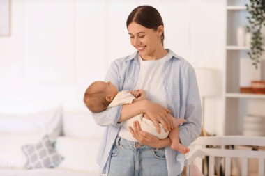 Anne küçük bebeğini yatak odasında tutuyor.