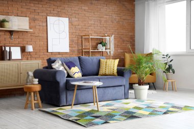 Oturma odasının içinde mavi kanepe, koltuk ve palmiye ağaçları var.