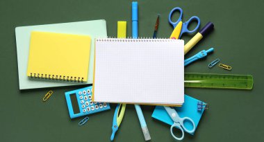 Yeşil arka planda birçok okul malzemesi, üst manzara