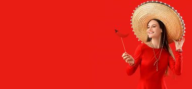 Sombrero şapkalı ve kırmızı arka planda kırmızı biberli güzel bir kadın.