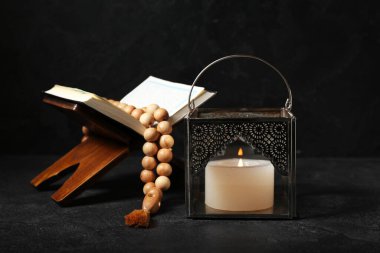 Müslüman lambası, yanan mum, Kuran ve koyu arkaplanda dua boncukları