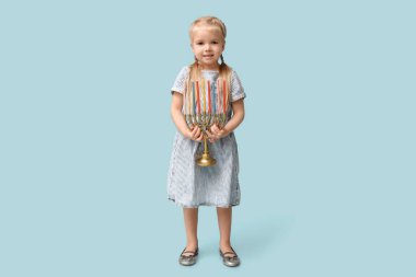 Mavi arka planda menorası olan şirin, mutlu küçük bir kız. Hanuka kutlaması