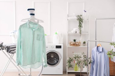 Çamaşır makinesi, elbise askılığı ve buharlı şık çamaşır odasının içinde.