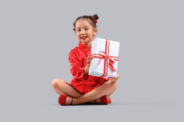 Gri arka planda oturan şirin Asyalı kız. Çin Yeni Yıl Kutlaması