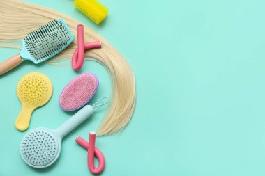 Sarı iplikli farklı saç fırçaları ve turkuaz arka planda bigudiler.