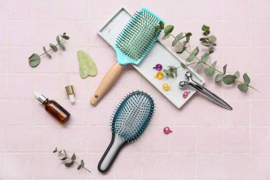 Yüz masajlı saç fırçaları, bir şişe kozmetik ürünü ve pembe kapsüller.