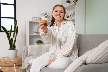 Evde tıbbi sprey kullanan boğazı ağrıyan hasta genç bir kadın.