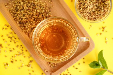 Sarı arka planda bir bardak lezzetli karabuğday çayı ve nane şekeri, yakın plan.