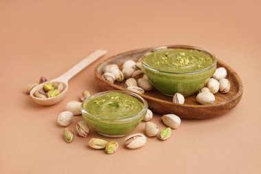 Ahşap tepsi, kaşık ve kâse kahverengi arka planda fıstık ezmesi.