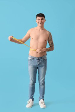 Mavi arka planda mezurası olan genç bir adam. Diyet kavramı