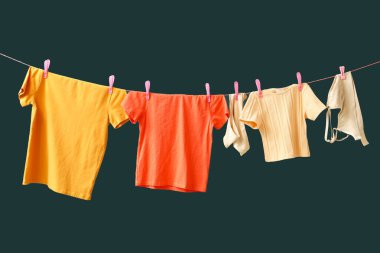 Yeşil arka planda ipte asılı farklı temiz kıyafetler.