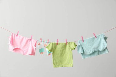 Gri arka planda ipte sallanan farklı temiz kıyafetler.