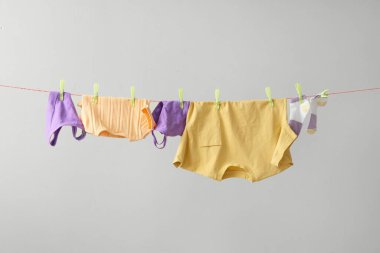 Gri arka planda ipte sallanan farklı temiz kıyafetler.