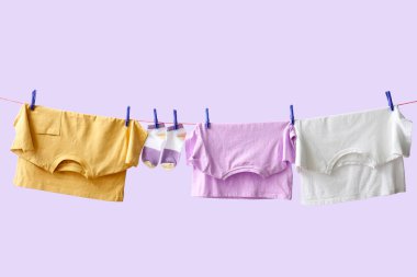 Temiz giysiler ipte leylak arka planda asılı.