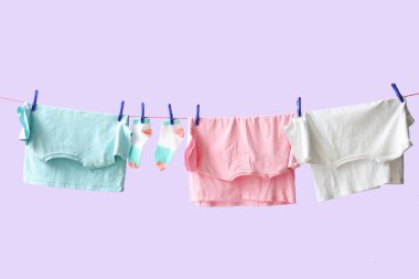 Temiz giysiler ipte leylak arka planda asılı.