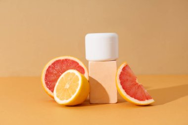 Kahverengi arka planda kozmetik ürün kavanozu, narenciye ve alçı standı ile kompozisyon