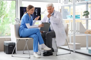 Klinikte hemşireyle çalışan olgun bir doktor.