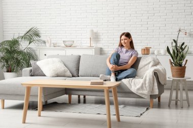 Oturma odasındaki rahat kanepede dinlenen güzel genç bayan.