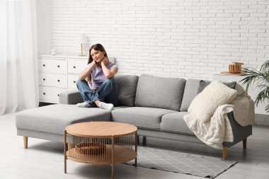 Oturma odasındaki rahat kanepede oturan güzel genç bayan.