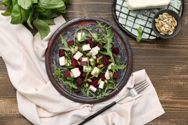 Ahşap arka planda çatal ve peçeteli taze sebze salatası.