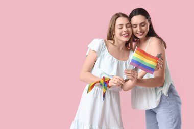 Pembe arka planda LGBT bayrağı olan güzel bir lezbiyen çift.