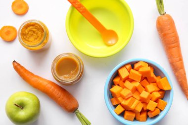 Sağlıklı bebek püresi kavanozları, gri arka planda malzemeler ve aksesuarlar.