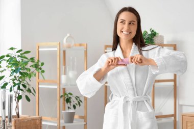 Evdeki banyoda deodorantı olan güzel, genç ve mutlu bir kadın.