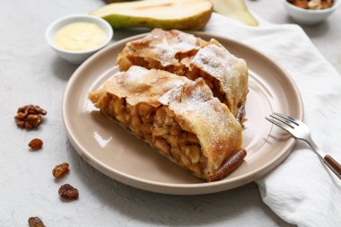 Gri arka planda lezzetli armut, fındık ve çatal parçaları olan bir tabak.