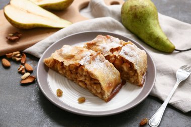 Gri grunge arka planda lezzetli armut turtası ve çatallı tabak.