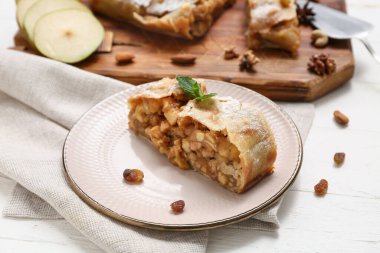 Lezzetli armutlu turta ve beyaz ahşap arka planda kuru üzüm tabağı.