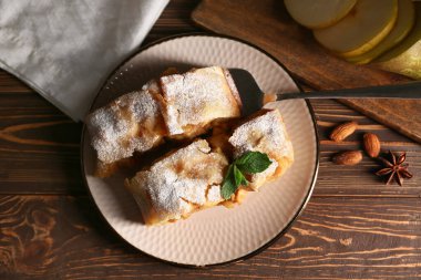 Ahşap zemin üzerinde armutlu turta ve spatula parçaları ile tabak